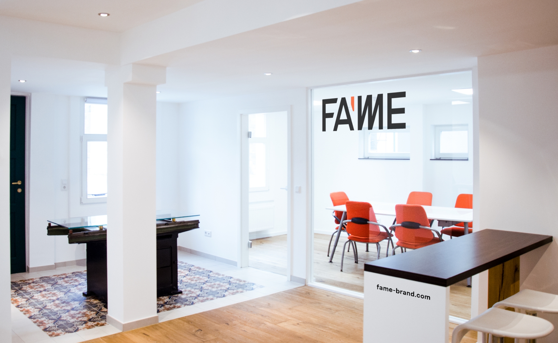 Modernes, helles Büro mit Fame-Branding und einem Konferenzraum mit orangefarbenen Stühlen.